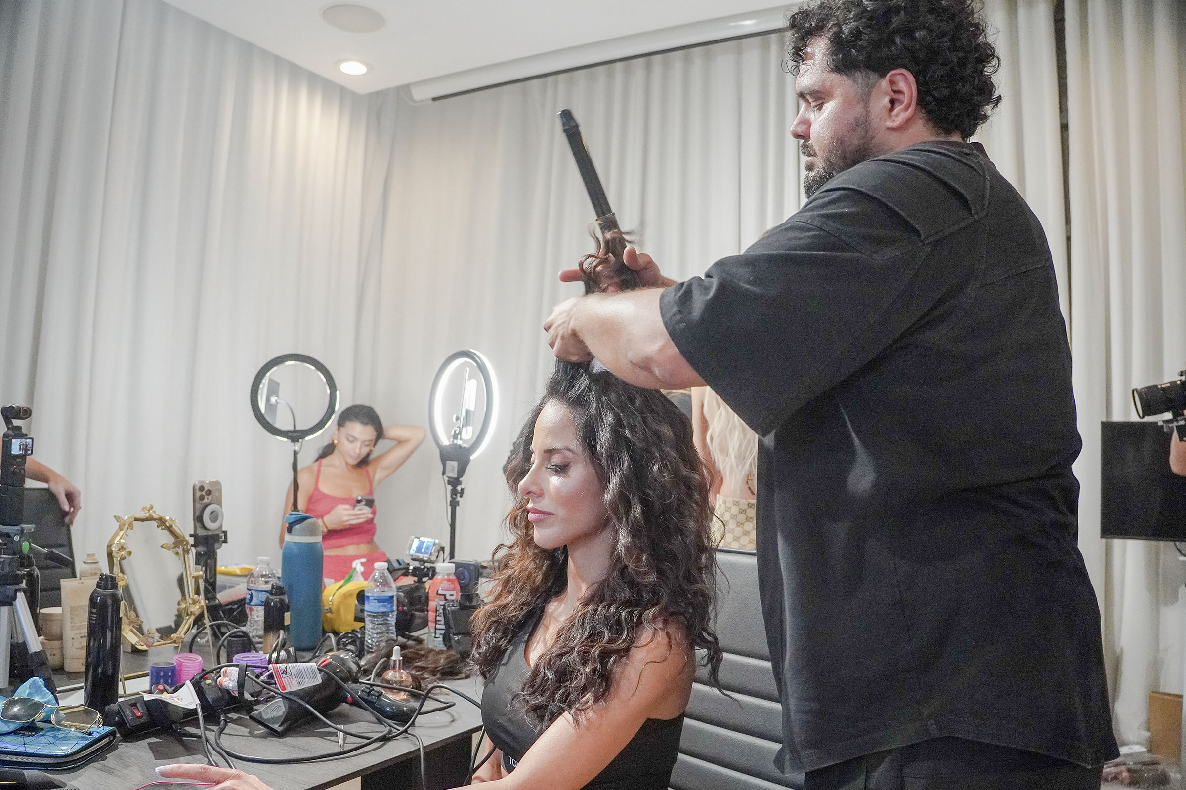 A hairstylist curls a model's hair backstage before the runway show.