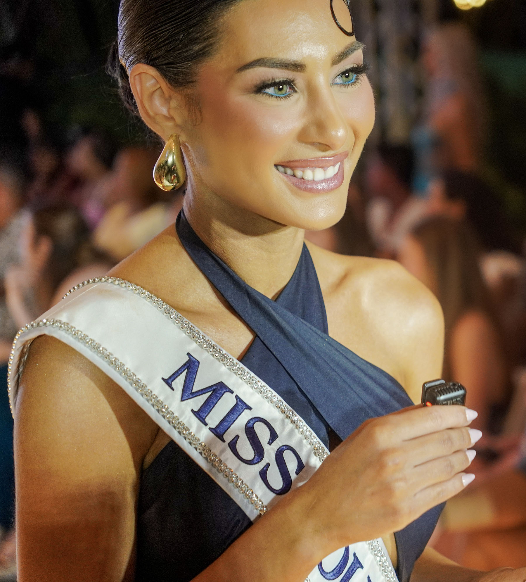 Pageant titleholder smiling between runway moments at The Deity Show.