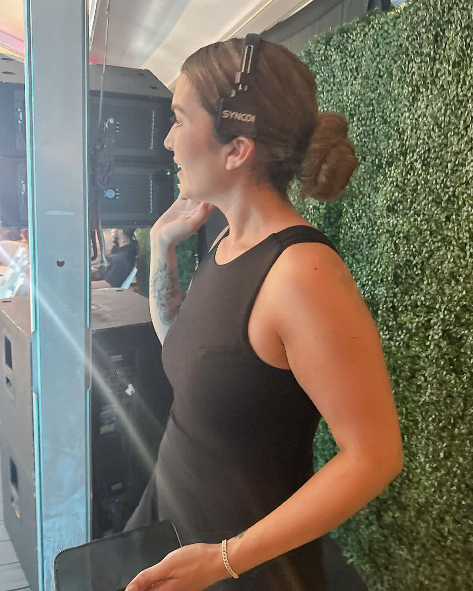 Vanessa Sims works in profile with a headset and production device beside the runway.